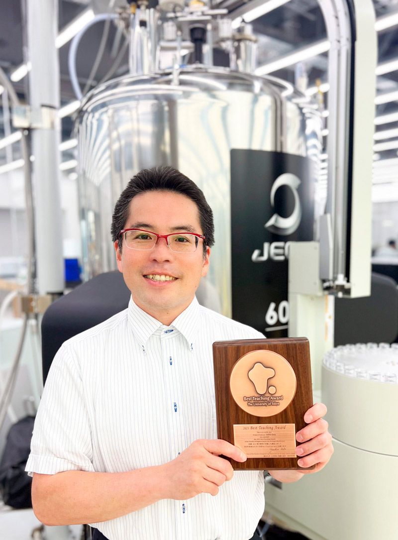 Best Teaching Award受賞記念の盾。NMR分子構造解析装置の前で Best Teaching Award受賞記念の盾。NMR分子構造解析装置の前で